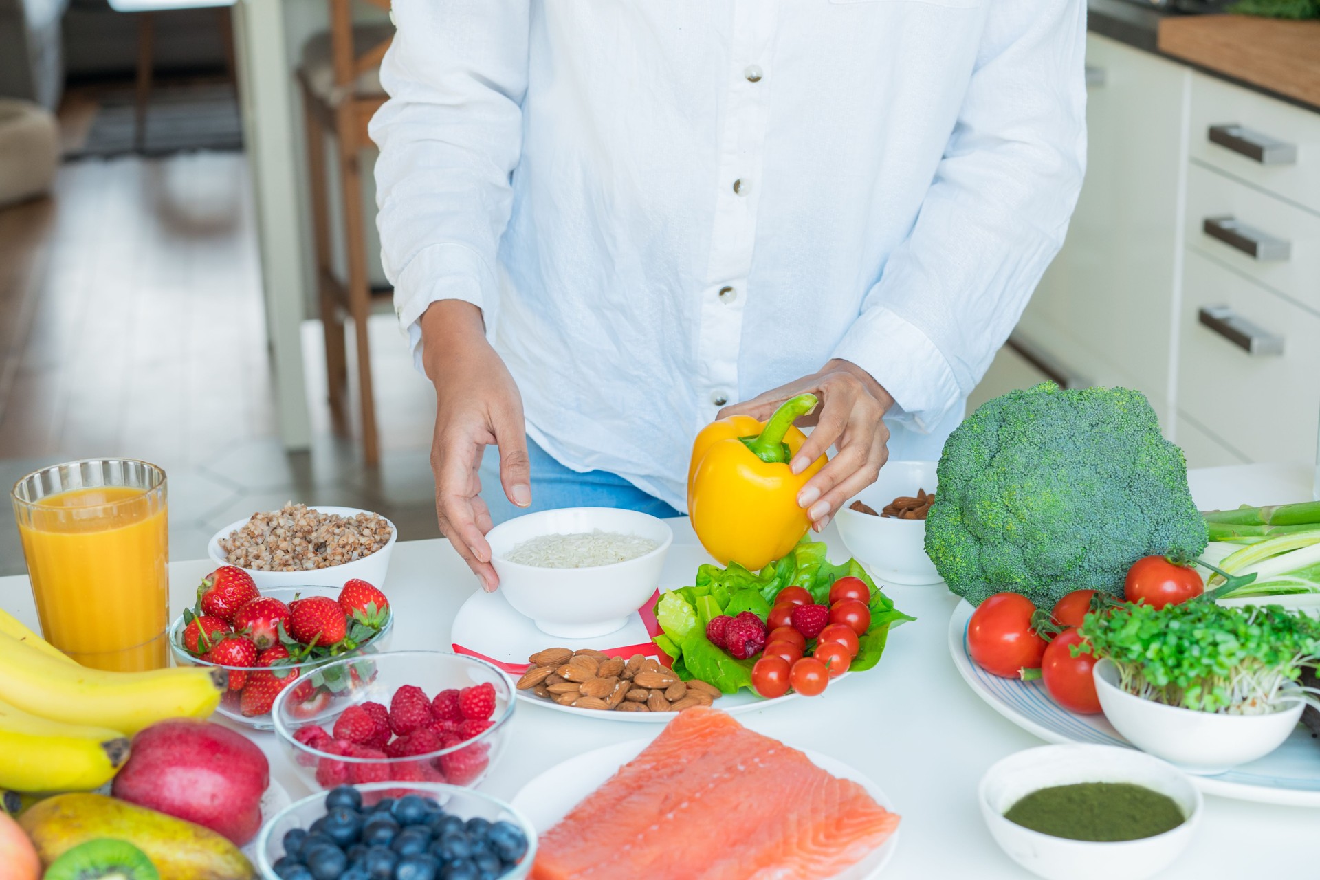 Female Nutritionist expert makes healthy balanced diet plate according to proportions of nutrients. Plate with pie chart of fruit, vegetables, grains, proteins on kitchen table with ingredients.